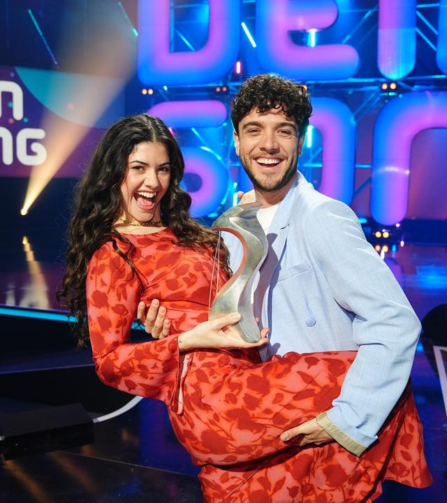 Jeannie Naomie Wagner und Luca Hänni stehen auf der "Dein Song" Bühne und halten den "Dein Song" Pokal in den Händen.