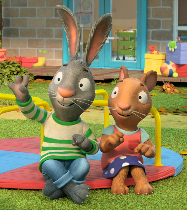 Frankie hält ein Klemmbrett in der Hand und stellt eine Frage. Pip und Posy sitzen auf dem Spielplatz und Pip hebt die Hand, um die Frage zu beantworten.