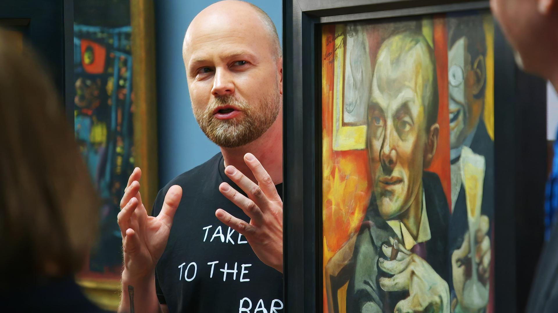 Ein Mann spricht vor einem Gemälde von Max Beckmann und gestikuliert mit den Händen.