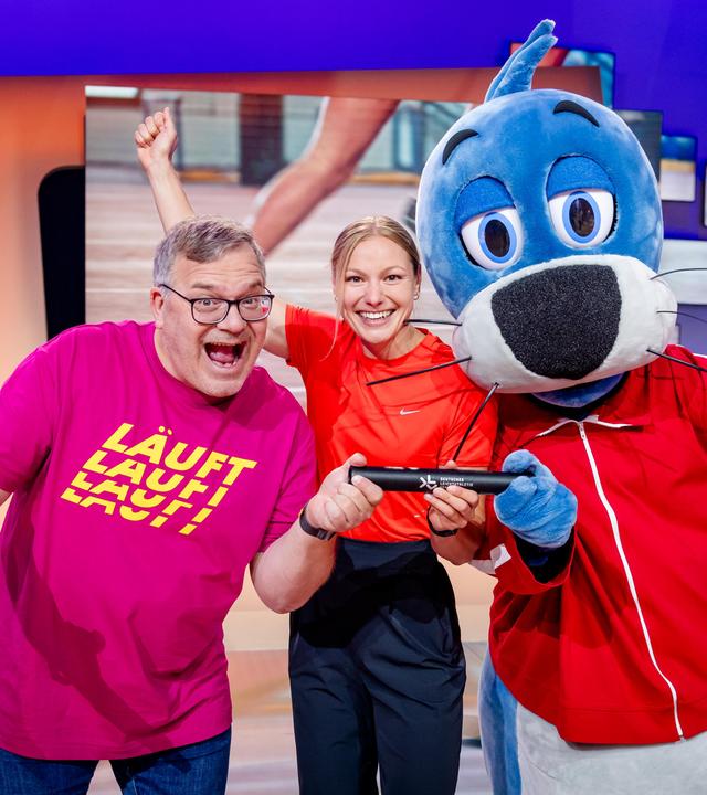 "1, 2 oder 3 - Das große Rennen": Elton, Sprinterin Lisa Mayer und Piet Flosse stehen im Studio vor dem "1, 2 oder 3"-Logo und strahlen in die Kamera.