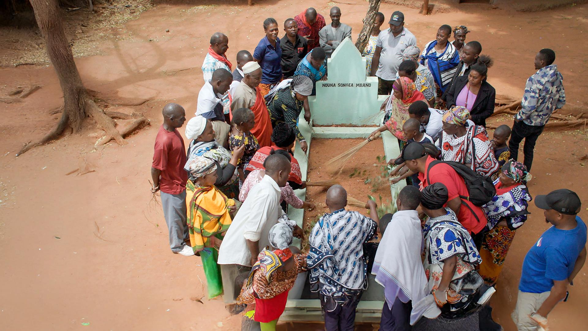 John Mbano, Aidan Mbano und ihre Familie gedenken dem ermordeten Songea Mbano an dessen Grab.