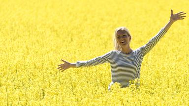 Saga (Nele Kiper) steht lachend im gelb blühenden Rapsfeld