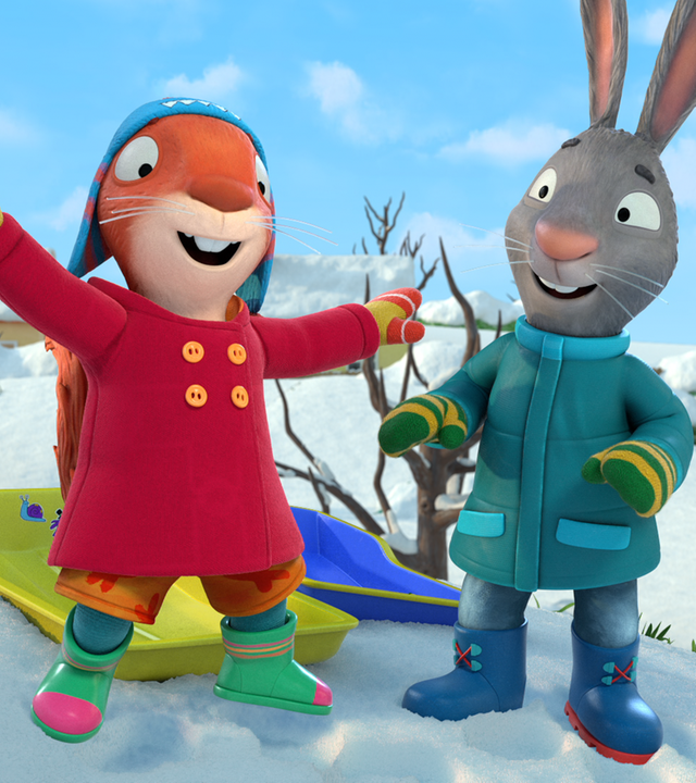 Jamila und Posy stehen vor ihren Schlitten. Jamila hat die Arme in die Luft geworfen.