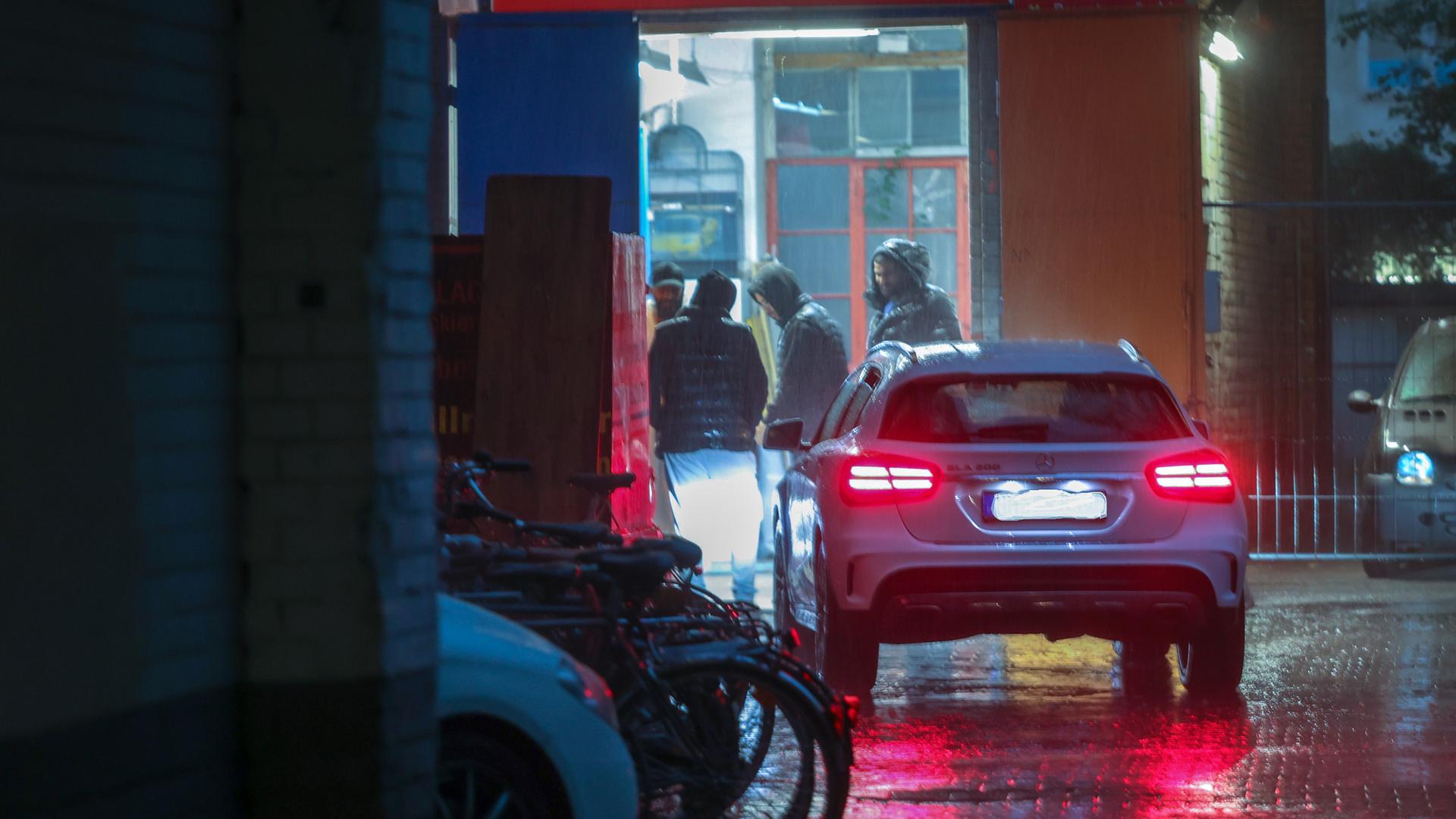 Männer in einer Autowerkstatt stehen im Halbdunkel zusammen