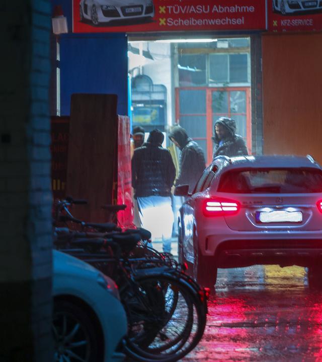 Männer in einer Autowerkstatt stehen im Halbdunkel zusammen