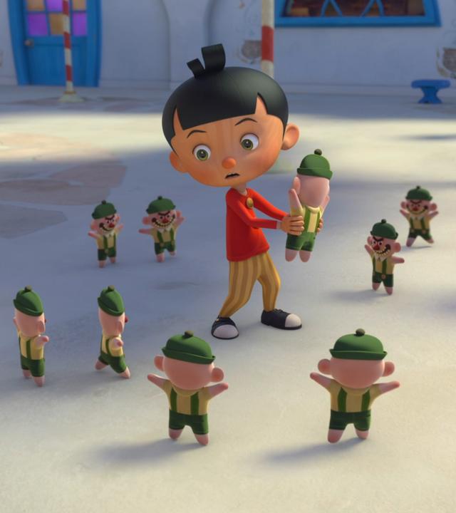 Pinocchio hält einen Streiche-Gnom in den Händen, schaut jedoch erschocken, da er umzingelt ist von acht weiteren Streiche-Gnome, die frech gucken und ihn umkreisen. Betulla ist im Hintergrund zu sehen und warnt Pinocchio mit ihrem Zauberstab in der Hand.