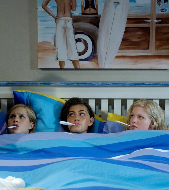 Emma, Cleo und Rikki iegen mit einem Fieberthermometer im Bett. Links daneben steht die Hausärztin.