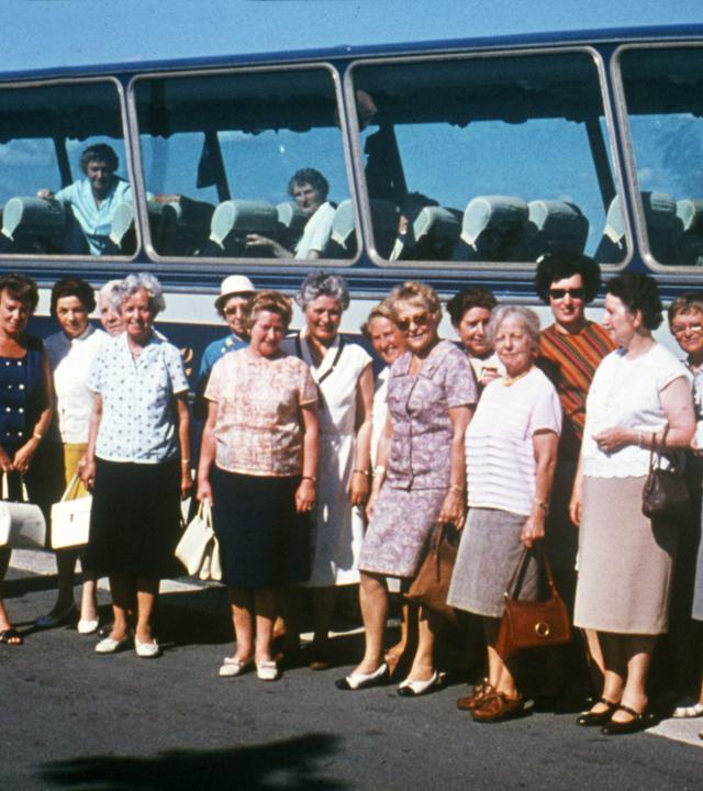 Mehrere ältere Damen stehen vor einem Bus.