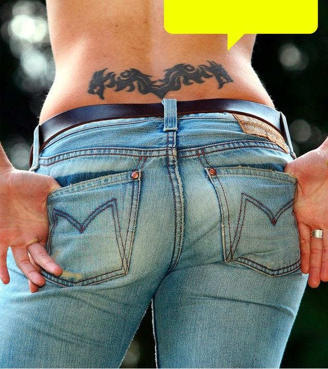 Eine Frau von hinten: über dem Bund einer Jeans ist ein Arschgeweih tätowiert.