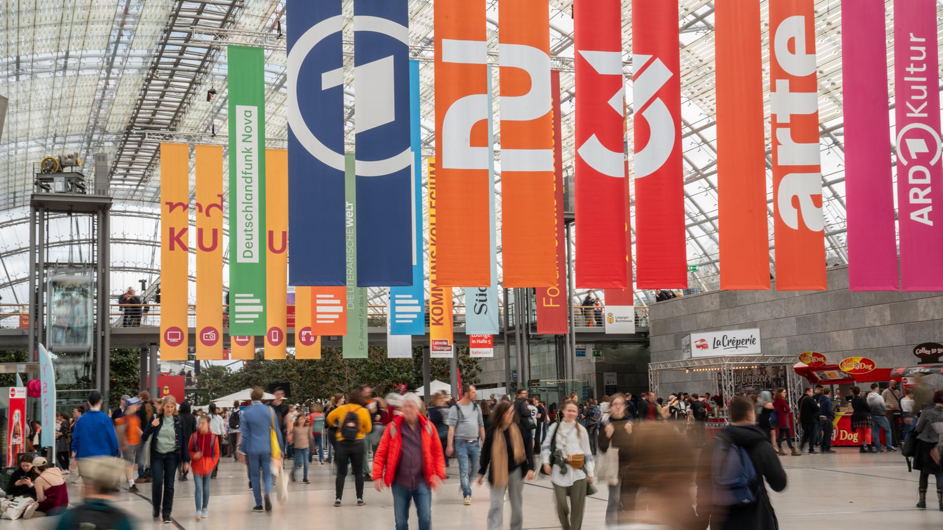 Blick in die Messehalle der Messe Leipzig anlässlich der Leipziger Buchmesse: Fahnen von ARD, ZDF, 3sat und arte hängen von der Decke, Menschenmenge in der Halle