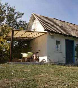 Ein kleines Haus im Grünen bei Sonnenschein.