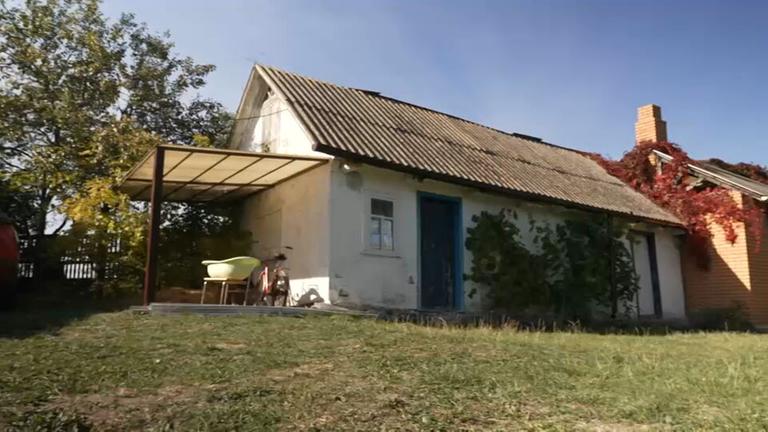 Ein kleines Haus im Grünen bei Sonnenschein.
