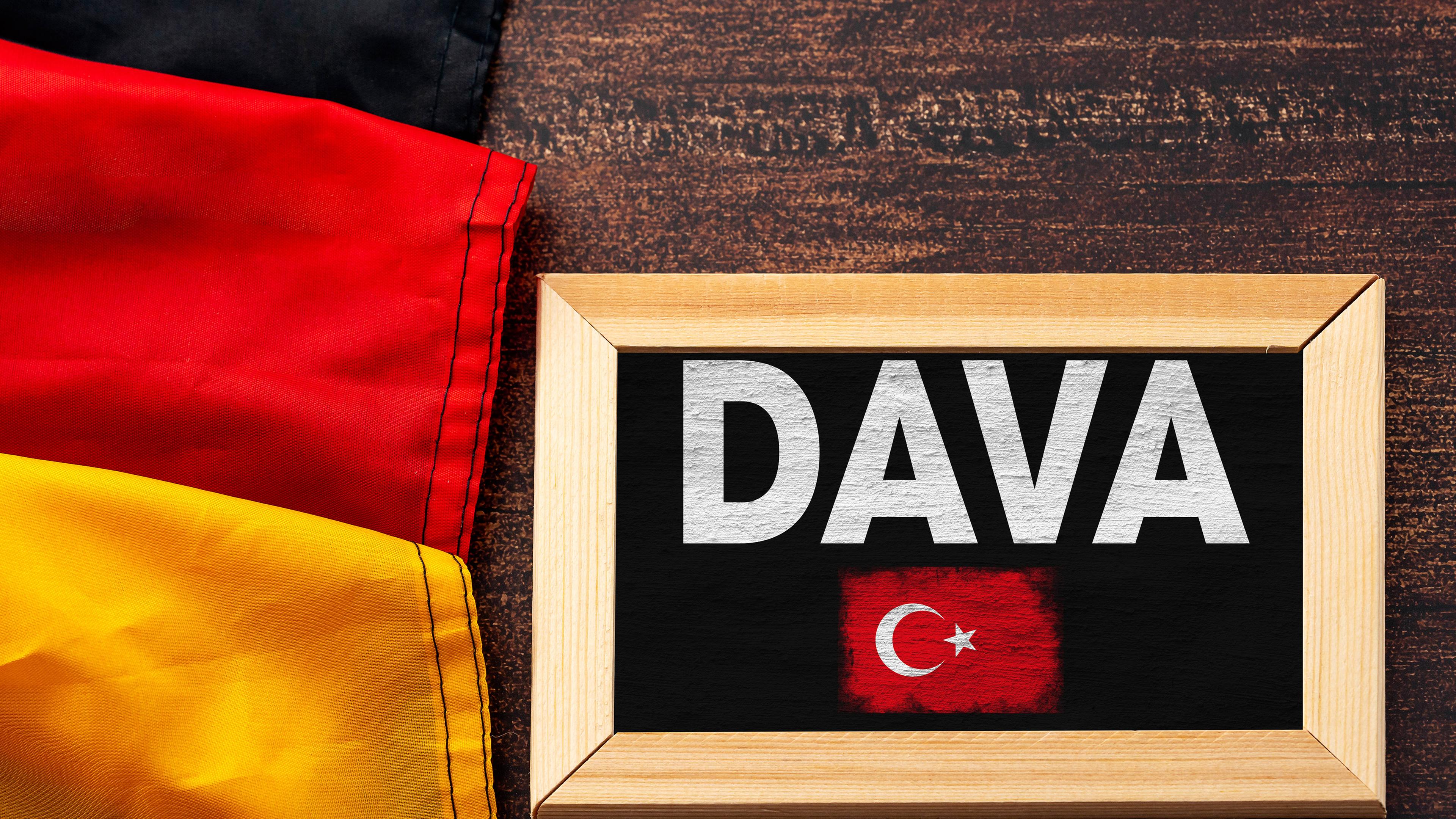 Neben der Deutschlandflagge liegt eine schwarze Tafel mit der Aufschrift DAVA und einer kleinen aufgemalten türkischen Flagge.