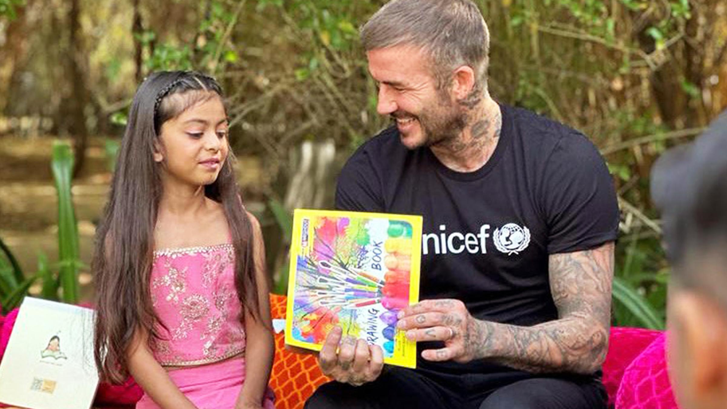 David Beckham sitzt neben einem jungen Mädchen.