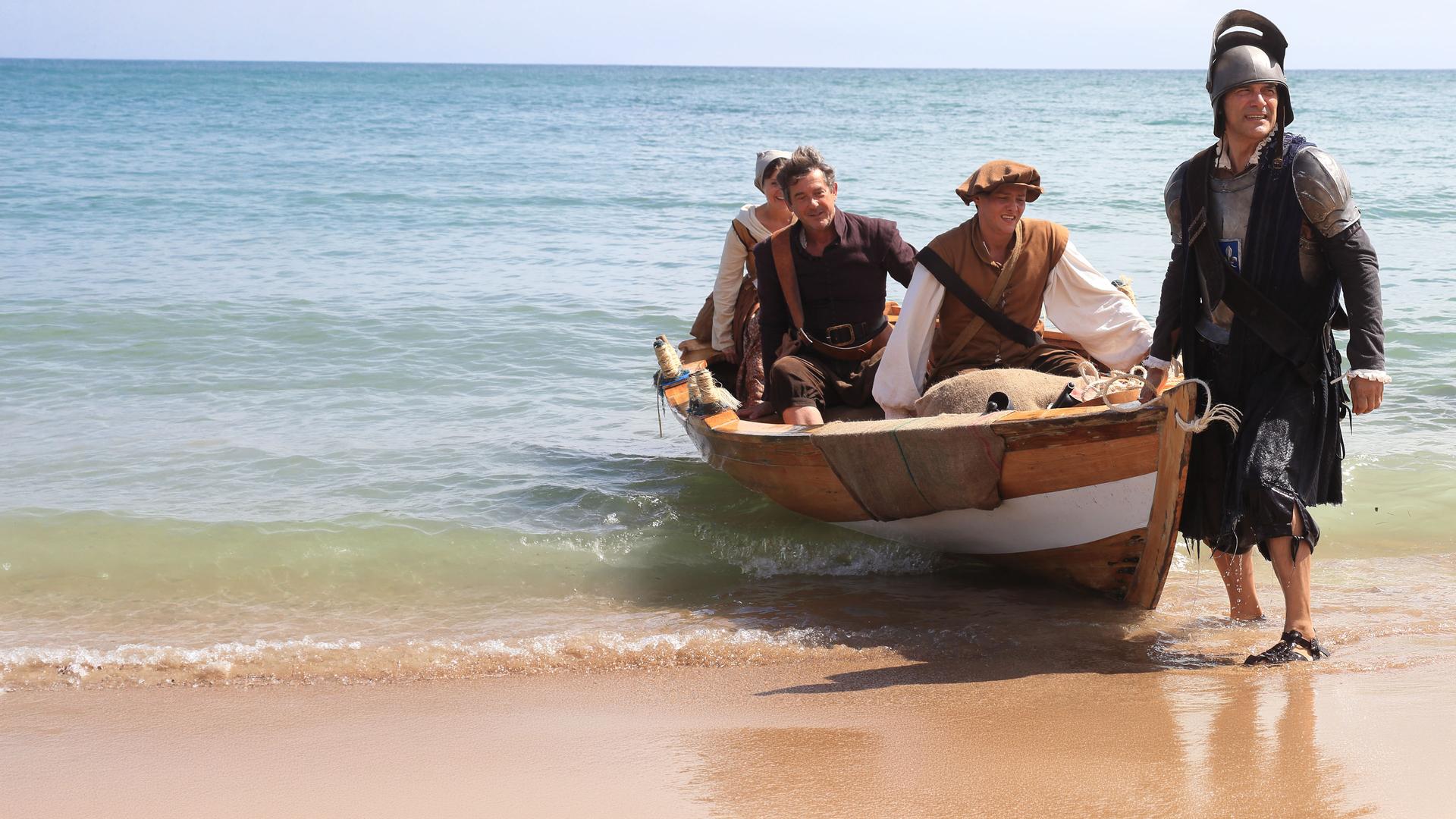 "Death in Paradise -  Ein bitterer Nachgeschmack": Teresa (Amanda Root), Henri (Georges Corraface), Ryan (Tyger Drew-Honey) und Francis Davis (Adrian Lukis) tragen altertümliche Kostüme und landen mit einem Boot am Ufer an.