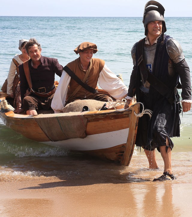 "Death in Paradise -  Ein bitterer Nachgeschmack": Teresa (Amanda Root), Henri (Georges Corraface), Ryan (Tyger Drew-Honey) und Francis Davis (Adrian Lukis) tragen altertümliche Kostüme und landen mit einem Boot am Ufer an.