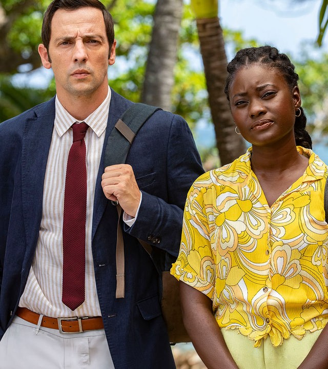 "Death in Paradise - Feuer im Herzen": Detective Neville Parker (Ralf Little) und Naomi Thomas (Shantol Jackson) stehen Seite an Seite und starren geradeaus.