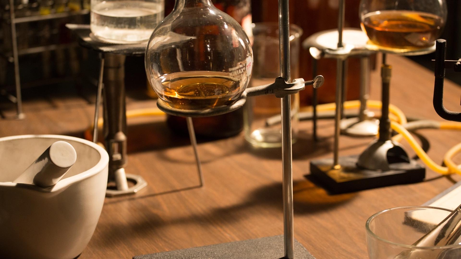 "Deep Time History: Der Weg in die Moderne": Glaskolben mit Flüssigkeit stehen auf einem Tisch.