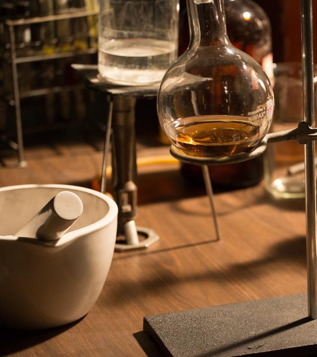 "Deep Time History: Der Weg in die Moderne": Glaskolben mit Flüssigkeit stehen auf einem Tisch.