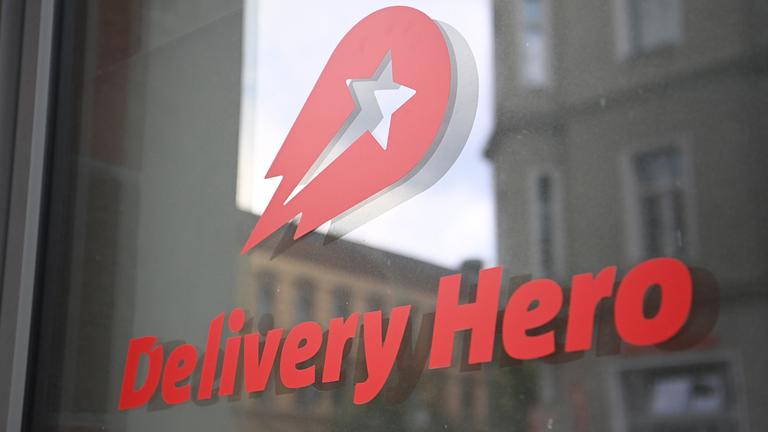 Logo und Schriftzug des Essenslieferdienstes Delivery Hero ist an einer Glasscheibe der Zentrale angebracht.