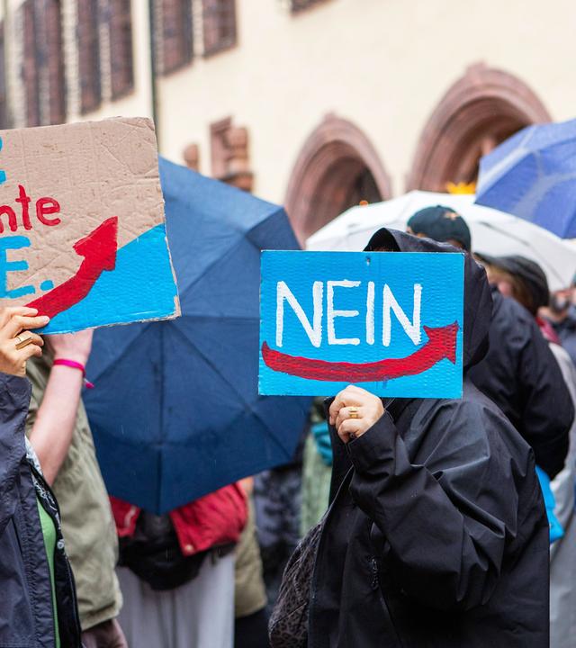 Bei einer Demonstration halten Menschen, die unter Regenschirmen nicht zu erkennen sind, Plakate gegen die AFD.