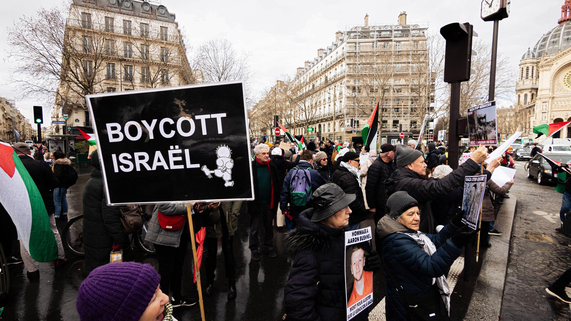Demonstration gegen Israel in Paris. Eine Menschenmenge mit palästinensischen Flaggen und Schildern. Auf einem steht: Boycott Israel.