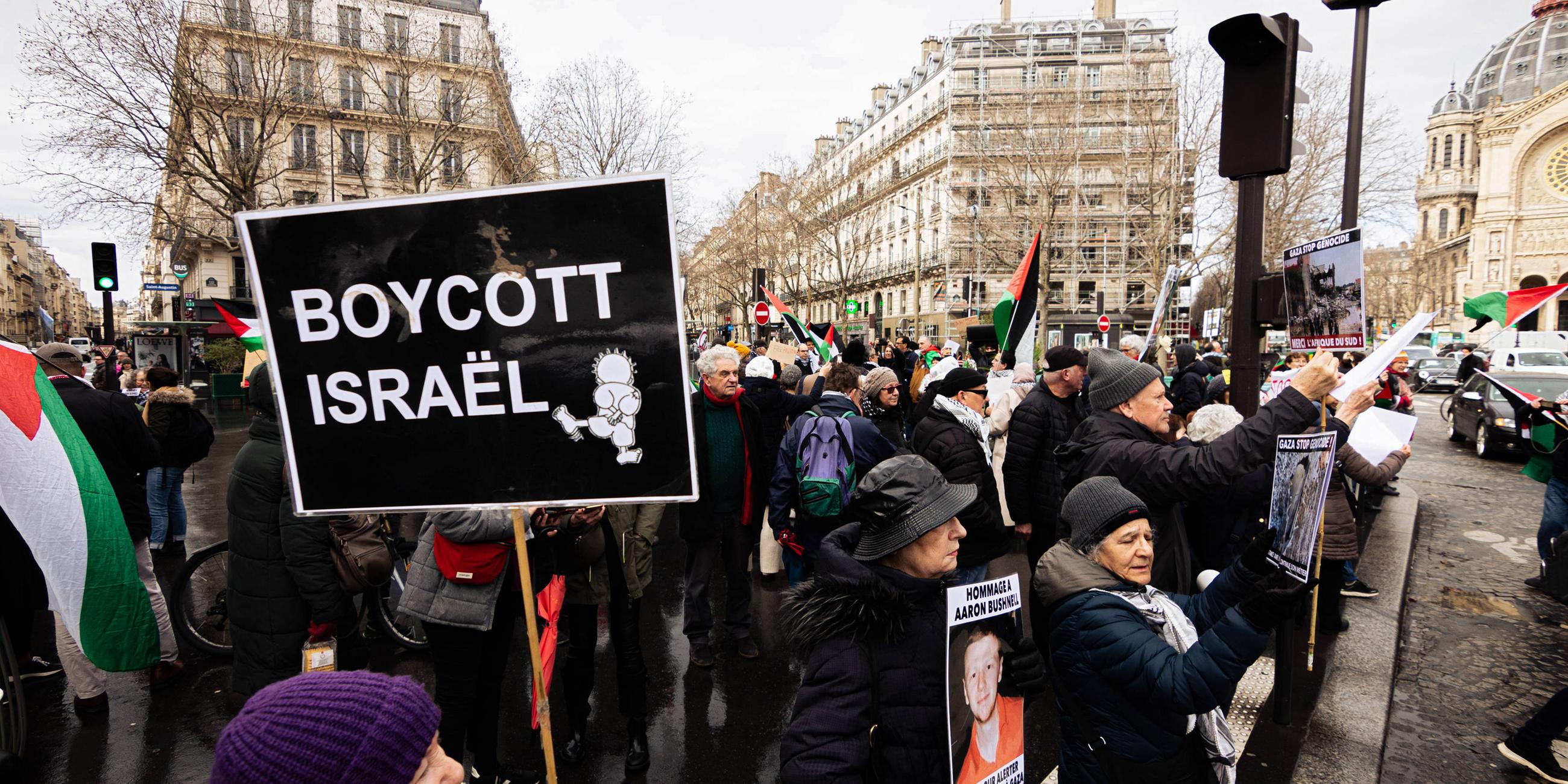 Demonstration gegen Israel in Paris. Eine Menschenmenge mit palästinensischen Flaggen und Schildern. Auf einem steht: Boycott Israel.