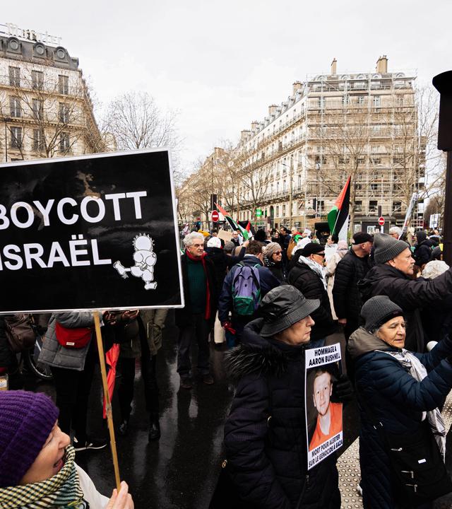 Demonstration gegen Israel in Paris. Eine Menschenmenge mit palästinensischen Flaggen und Schildern. Auf einem steht: Boycott Israel.