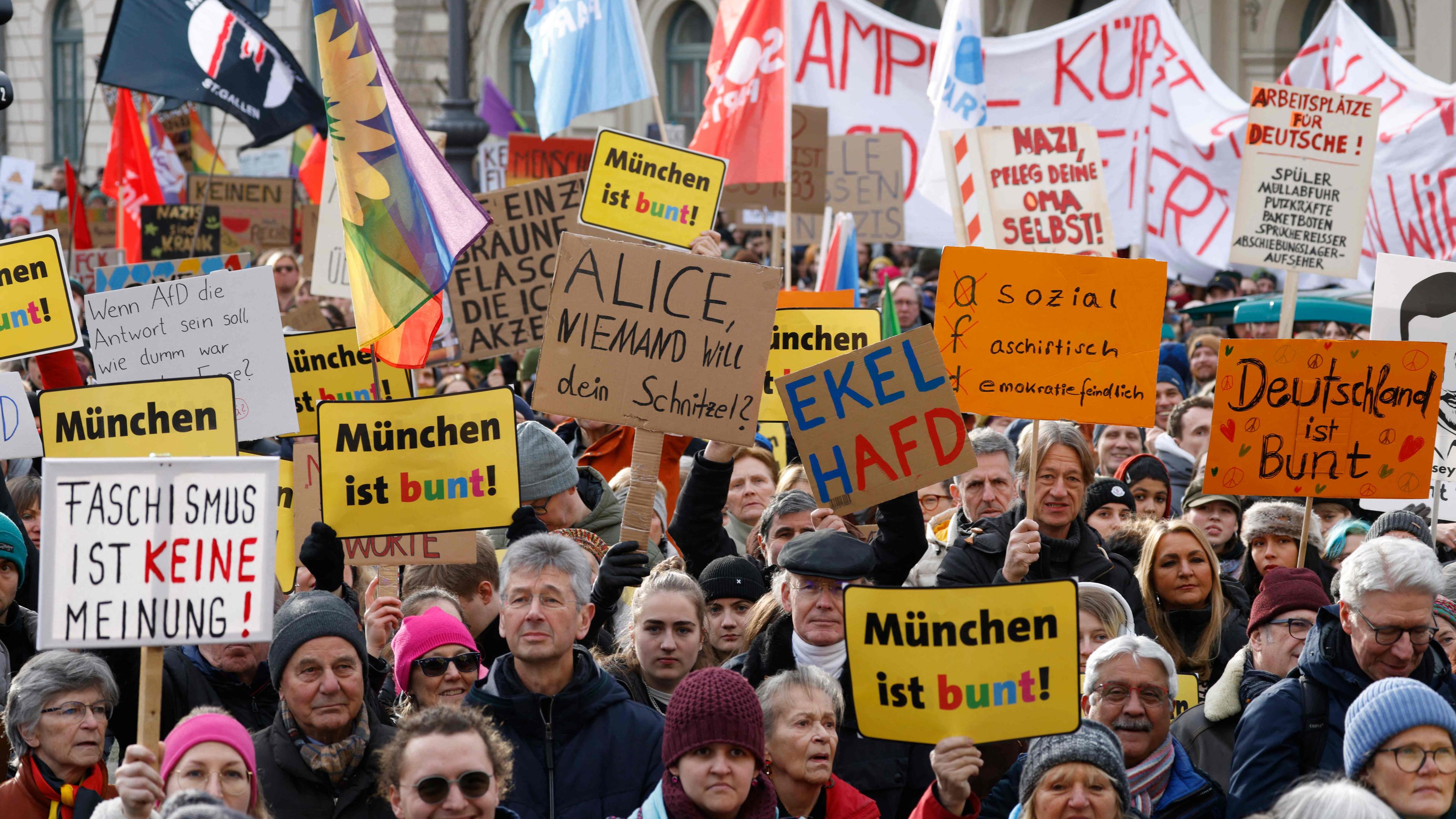 Participants hold up placards reading 'Munich is colourful' and 'Fascism is not an opinion' during a demonstration against racism and far-right politics in Munich, southern Germany on January 21, 2024. 