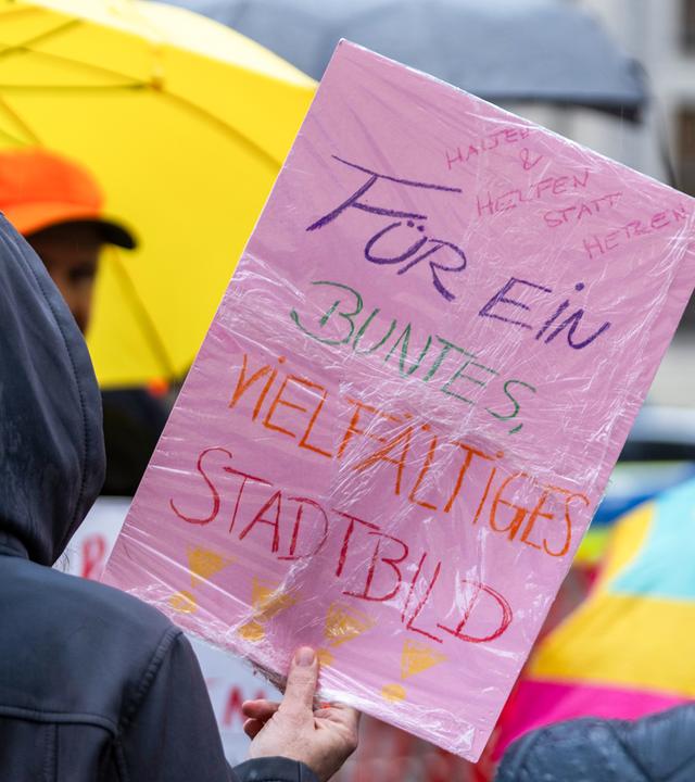 Im strömenden Regen demonstrieren Menschen auf dem Odeonsplatz. Unter anderem rief der Bayerische Flüchtlingsrat zu dieser Demonstration gegen die Stadtbild-Aussage des Bundeskanzlers auf. 