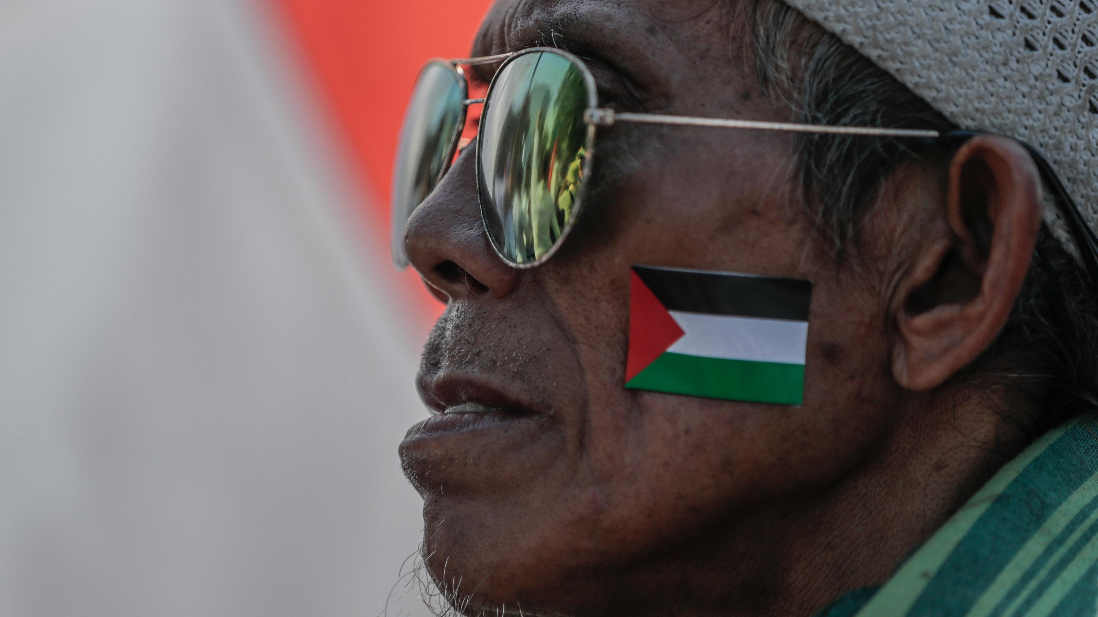Ein Mann mit einem Aufkleber mit der palästinensischen Flagge auf der Wange nimmt an einer Solidaritätskundgebung für die Palästinenser teil.