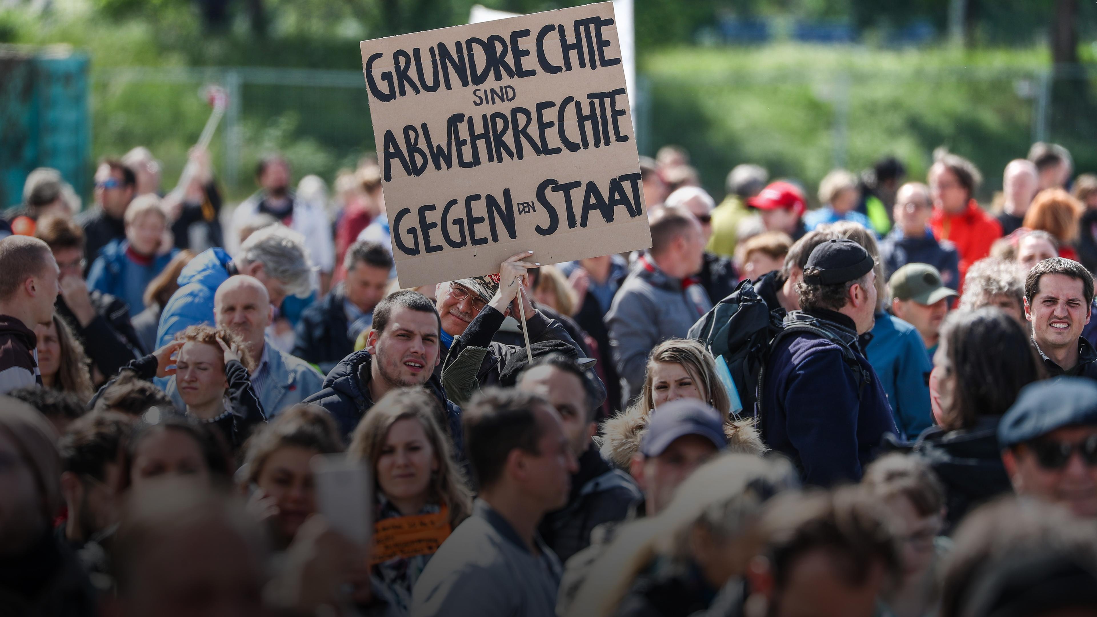 Menschenmasse die in Stuttgart demonstriert, eine Person hält ein Schild mit der Aufschrift: "Grundrecht sind Abwehrrechte gegen den Staat"