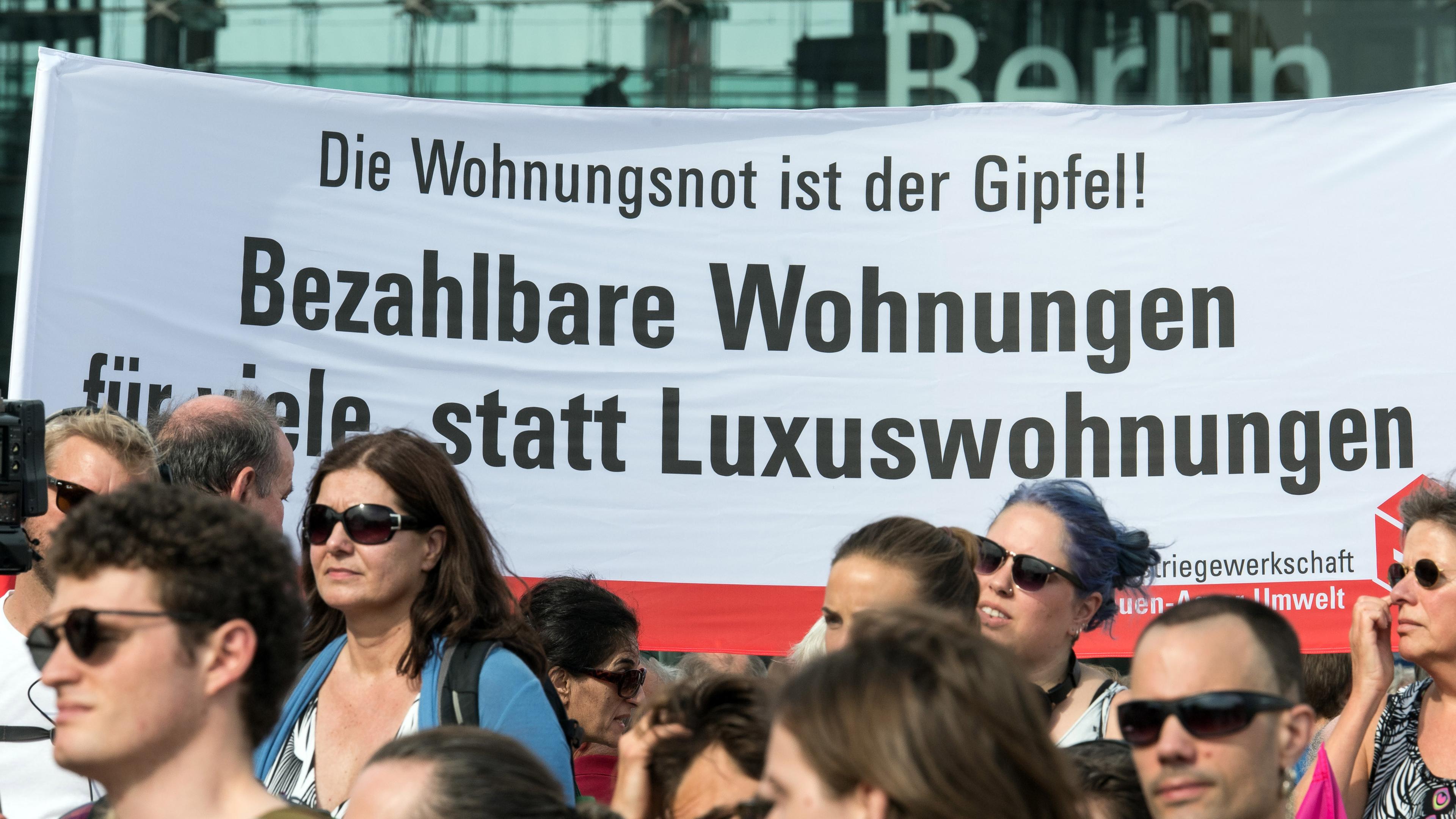 eilnehmer einer kundgebung demonstrieren unter dem motto «zusammen gegen #mietenwahnsinn» mit einem transparent "die wohnungsnot ist der gipfel! bezahlbare wohnungen fuer viele statt luxuswohnungen". 