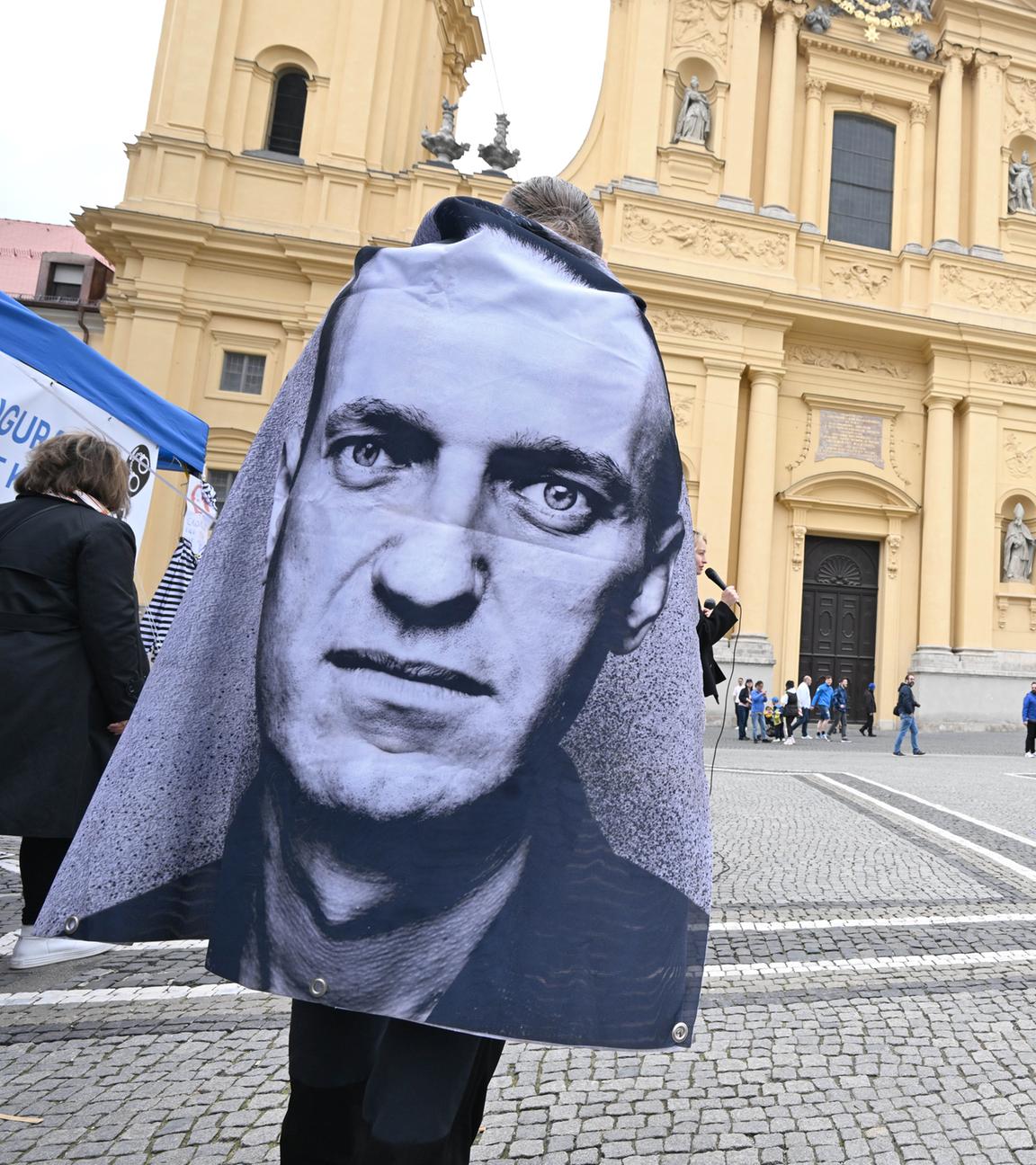 Bayern, München: Ein Demonstrant trägt einen Umhang mit einem Bild von Alexej Nawalny