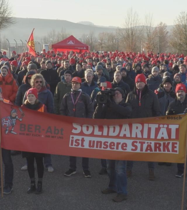 Bosch-Mitarbeitende demonstrieren gegen Arbeitsplatzabbau im baden-württembergischen Abstatt, halten im Vordergrund ein Transparent mit der Aufschrift: "Solidarität ist unsere Stärke"