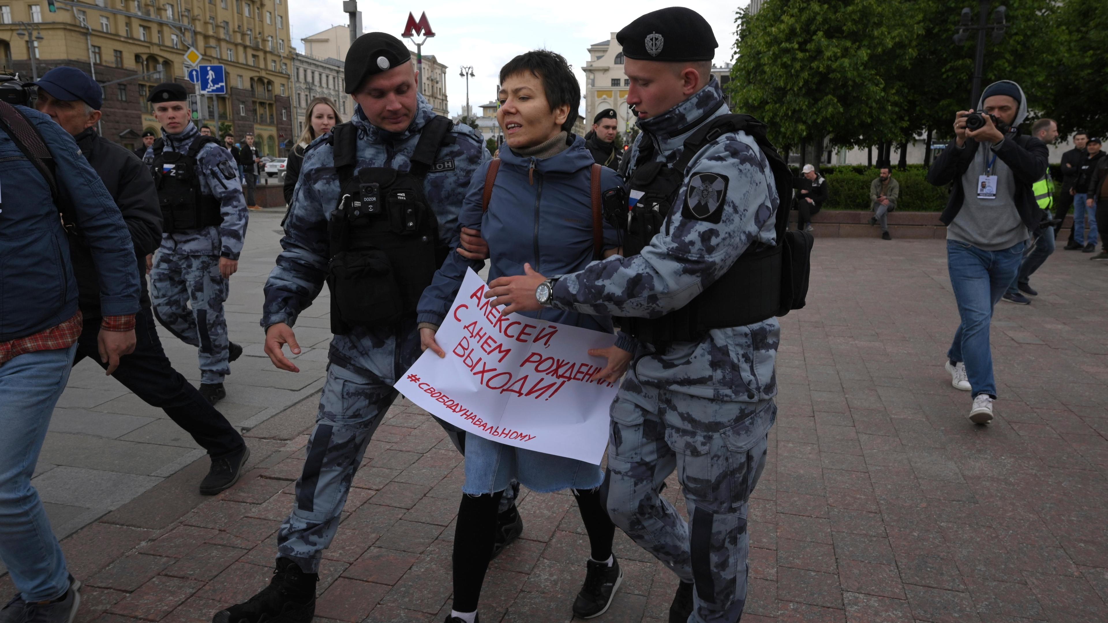 Russland, Moskau: Polizisten führen eine Demonstrantin auf dem Puschkinskaja-Platz ab, die ein Plakat mit der Aufschrift «Happy Birthday Alexej» trägt. 