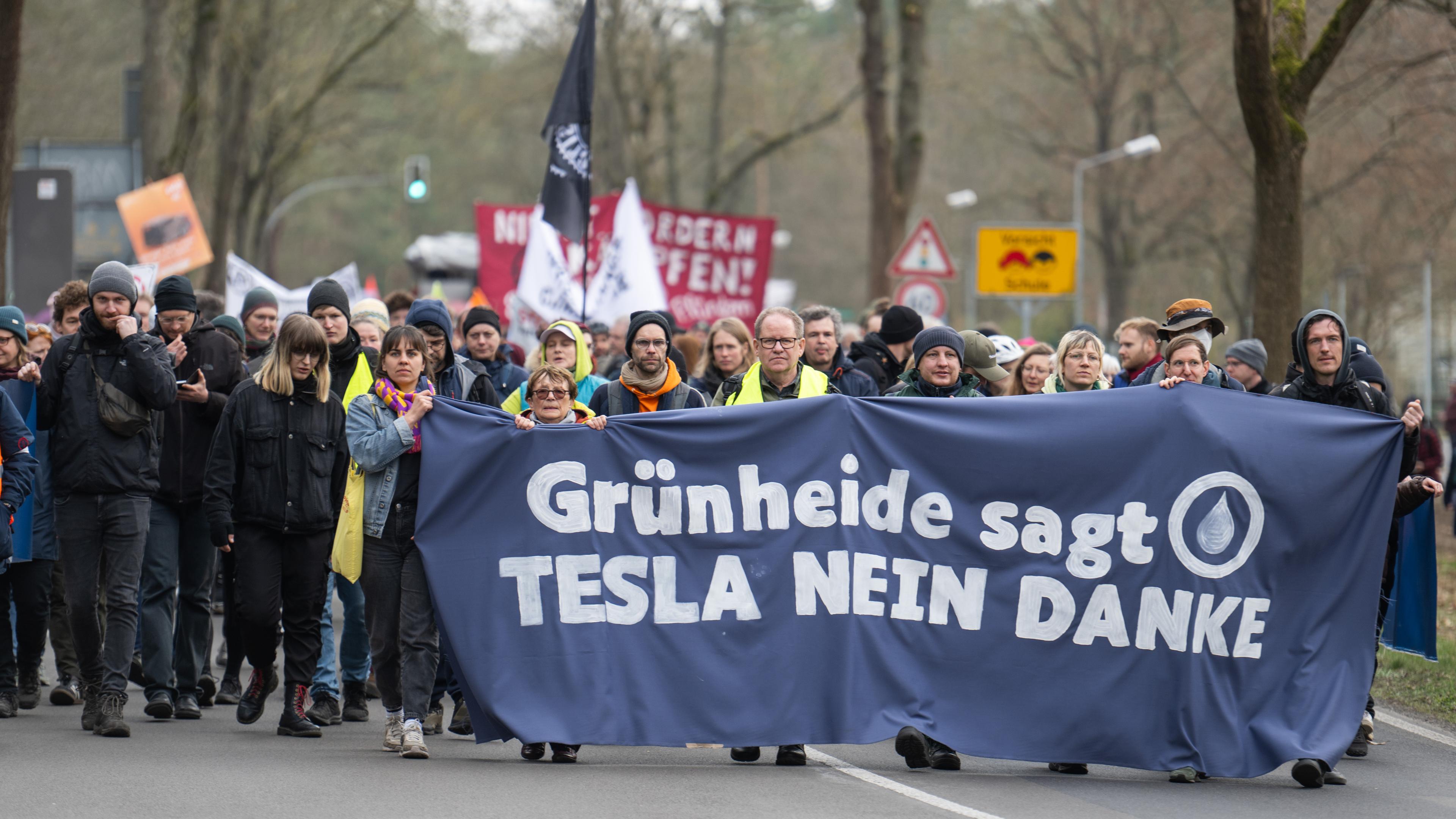 Bei einer Demonstration gegen die Tesla-Erweiterung unter dem Motto «Tesla Nein Danke!» tragen Teilnehmer ein Transparent mit der Aufschrift "Grünheide sagt Tesla nein danke".