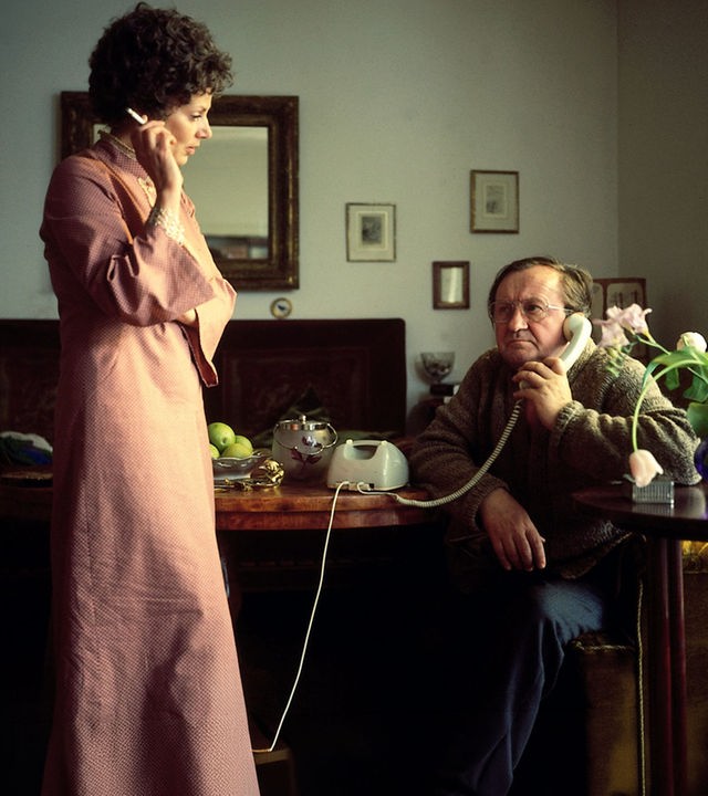 Hauptkommissar Köster (Siegfried Lowitz) sitzt telefonierend an einem mit grünen Äpfel gedeckten Tisch und schaut zu seiner Bekannten (Xenia Pörtner). Sie steht vor dem Schreibtisch, hält eine Zigarette in der rechten Hand und schaut Hauptkommissar Köster an.
