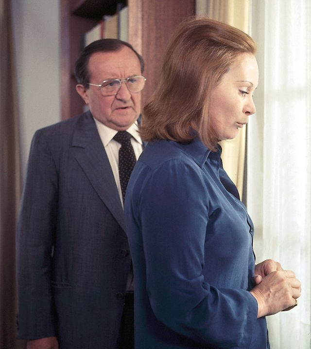 Hauptkomissar Köster (Siegfried Lowitz) und Verena Moldau (Krista Keller) stehen im Wohnzimmer vor einem Fenster. Köster spricht mit ihr und Verena hört zu. Sie schaut nachdenklich nach unten.