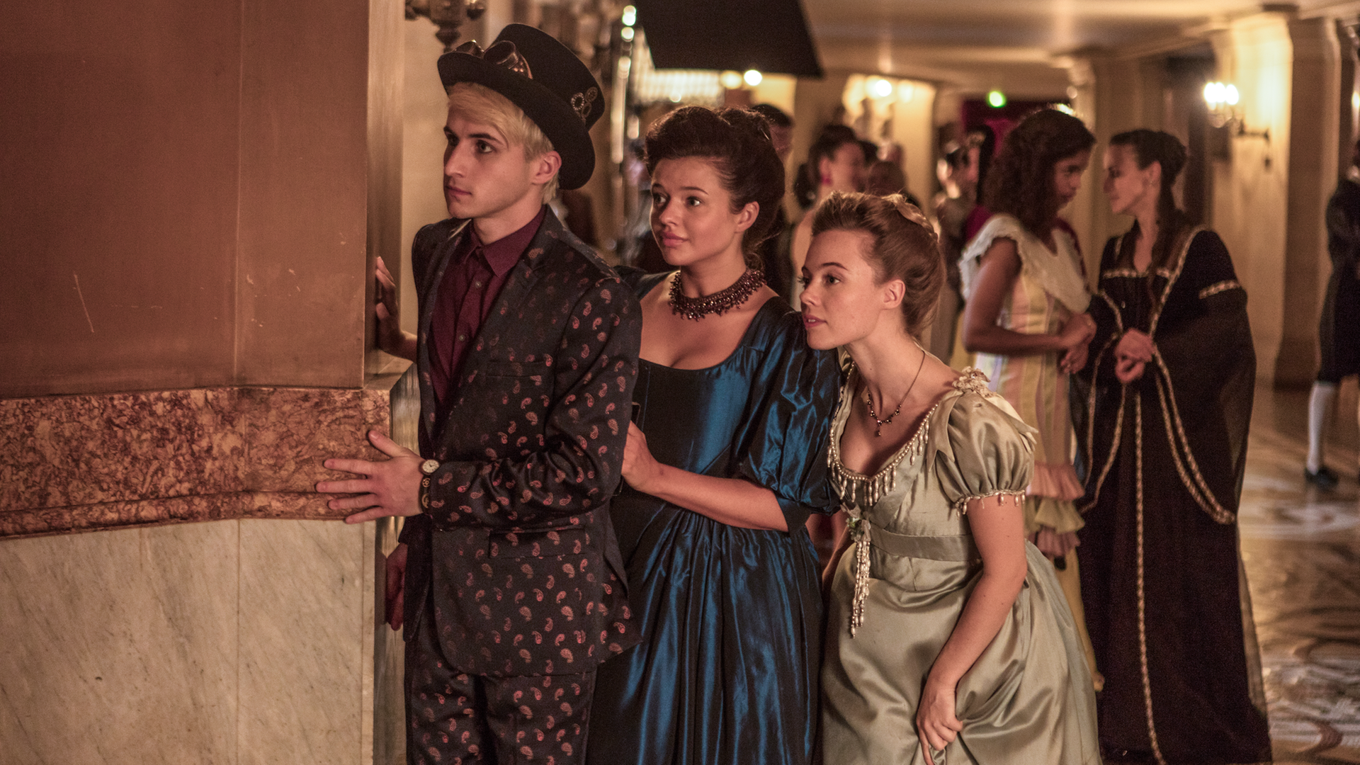 Frank (links), Kennedy (Mitte) und Bree (rechts) beobachten beim Ball der Zeitreisenden heimlich Lenas Mutter und Franks Vater, die sich angeregt unterhalten.