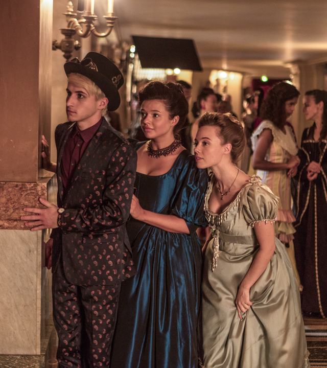 Frank (links), Kennedy (Mitte) und Bree (rechts) beobachten beim Ball der Zeitreisenden heimlich Lenas Mutter und Franks Vater, die sich angeregt unterhalten.