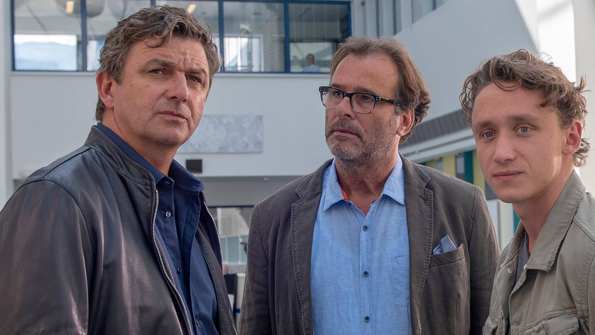 Im Krankenhaus unterhält sich Dr. Martin Gruber (Hans Sigl) mit Robert Metzinger (Joachim Raaf) und Chris Weigand (Aaron Friesz).