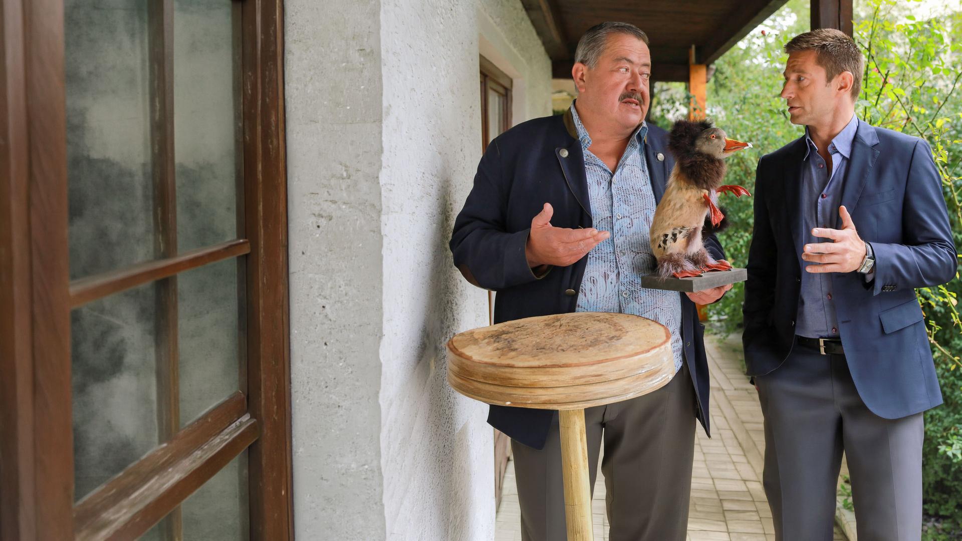 "Die Rosenheim-Cops - Der Fall der Felle": Vor einem Haus stehen die Kommissare Hofer (Joseph Hannesschläger) und Hansen (Igor Jeftic). Hofer hält einen Wolpertinger in der Hand.
