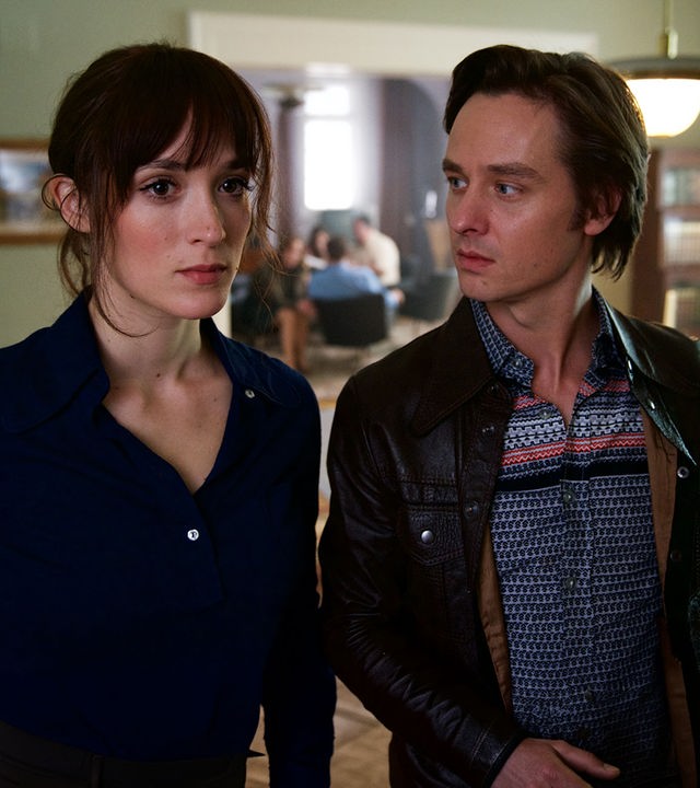 "Der gleiche Himmel (3)": Sabine Cutter (Friederike Becht) und Lars Weber (Tom Schilling) stehen Schulter an Schulter im Esszimmer der Familie Cutter. Lars schaut Sabine an. Im Hintergrund ist der Rest der Familie zu sehen.