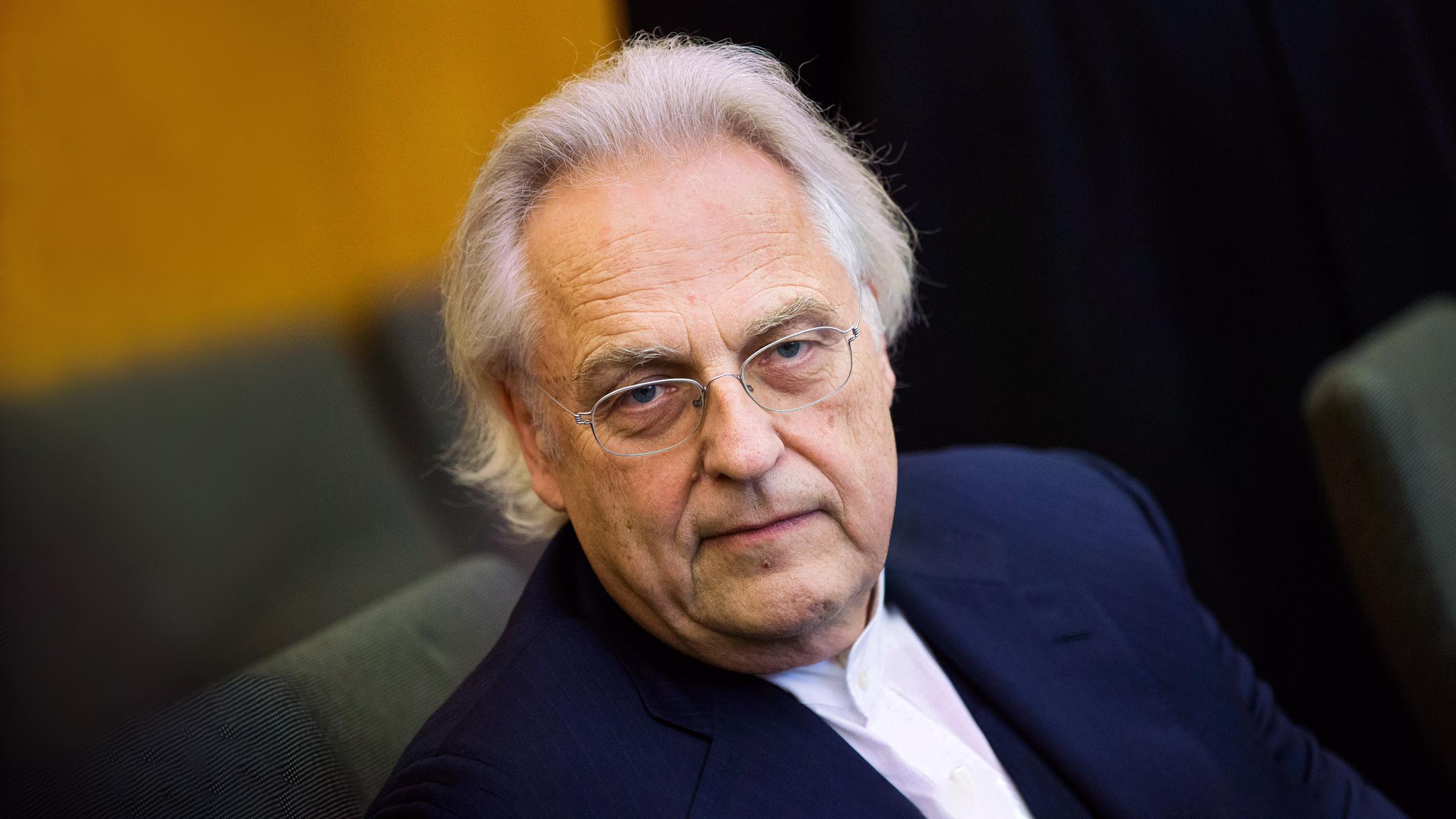 Ein weisshaariger Mann schaut den Betrachter an.