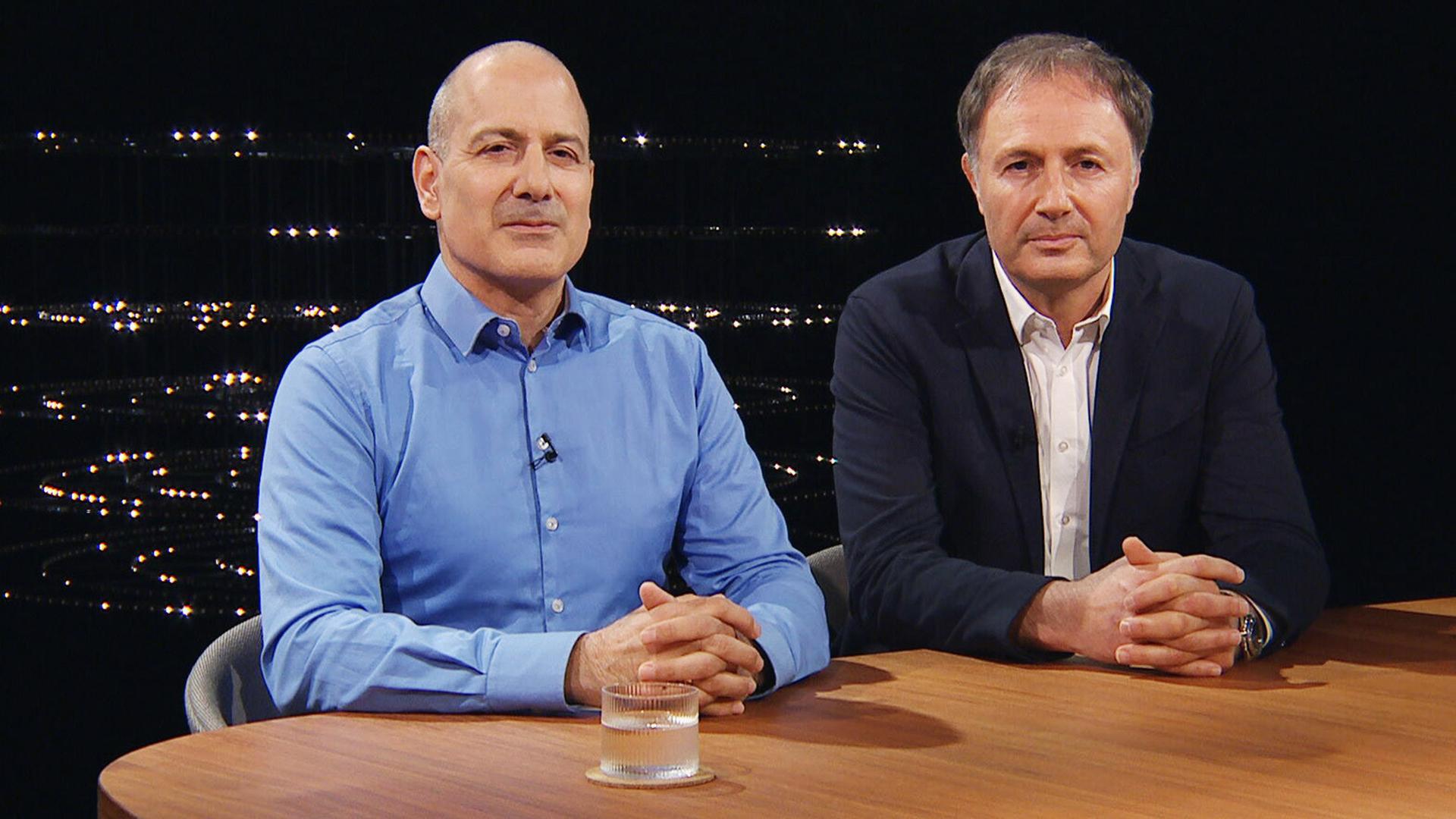 Zwei Männer sitzen an einem Holztisch