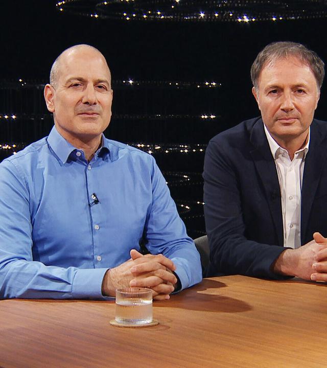 Zwei Männer sitzen an einem Holztisch