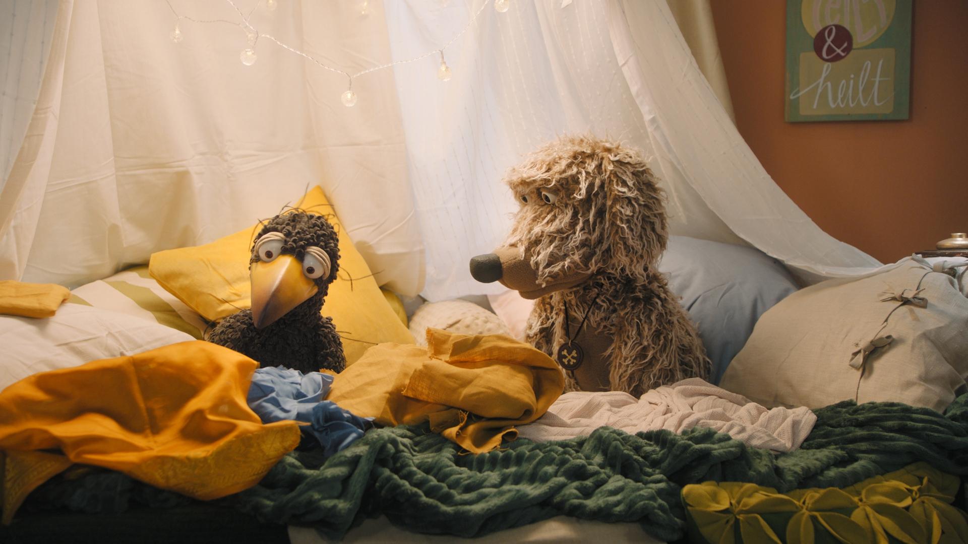 Rabe Rudi (rechts) sitzt mit Hund Buffo (links) in der gemütlichen Kuschelecke.