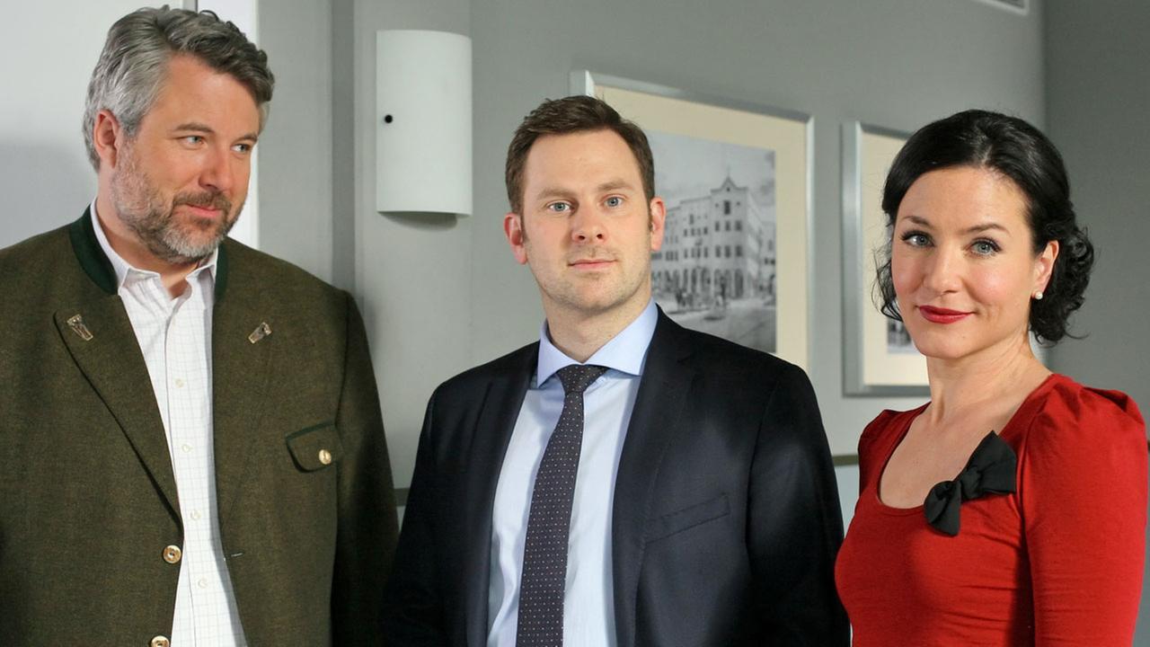 "Die Rosenheim-Cops - Der König kommt": Im Flur des Kommissariats stehen die Kollegen Stadler (Dieter Fischer), Sebastian König (Mark-Alexander Solf) und Sekretärin Stockl (Marisa Burger).