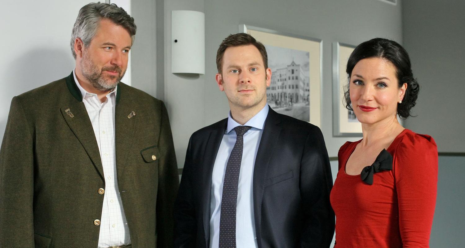 "Die Rosenheim-Cops - Der König kommt": Im Flur des Kommissariats stehen die Kollegen Stadler (Dieter Fischer), Sebastian König (Mark-Alexander Solf) und Sekretärin Stockl (Marisa Burger).